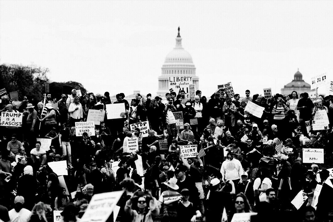 A large crowd of protesters holding signs with various messages, gathered at the U.S. Capitol building in the background. The atmosphere reflects a demonstration for civil rights and democracy, relevant to the theme of 'March 4 Democracy'.
